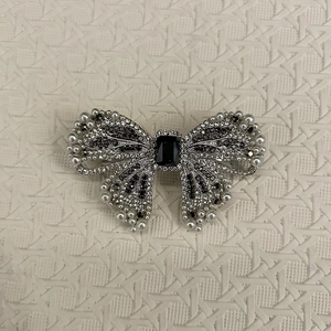 Detailed view of luxury bow hair clip featuring sparkling crystals and white pearls