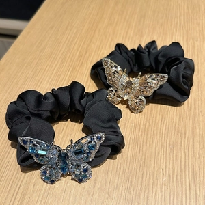 Detail of two crystal butterfly hair ties with blue and champagne rhinestones