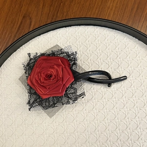 Detailed macro of a handmade red satin rose and black lace on an elegant hair clip