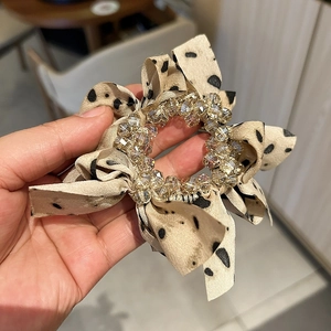 Detail view of polka dot mesh hair clip with champagne crystal bead center and satin layers