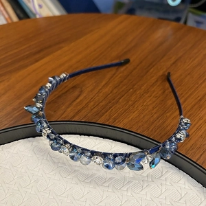 Détail d'un serre-tête en cristal bleu foncé avec strass sur une assiette blanche