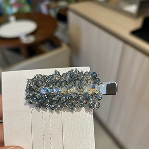 Detail of blue and clear crystal beads on a silver metal clip with square rhinestones