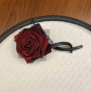 Detail view of handmade wine red satin rose hair clip with black lace and plastic base
