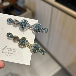 Detailed view of crystal bow hair clips with blue and tan teardrop stones on display card