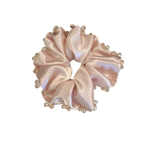 Champagne pink satin scrunchie with sparkling beaded edges for elegant hairstyling