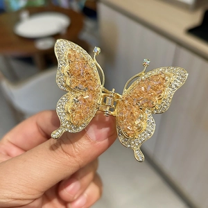 Gros plan sur la pince à cheveux papillon dorée avec cristaux champagne et strass