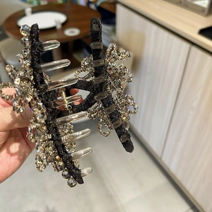 Handmade crystal hair claw clip with beaded petal design on a black fabric base