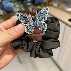 Close-up of elegant black satin hair tie featuring a sparkling blue crystal butterfly