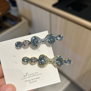 Detail of luxury crystal bow hair clips with blue rhinestones on a display card
