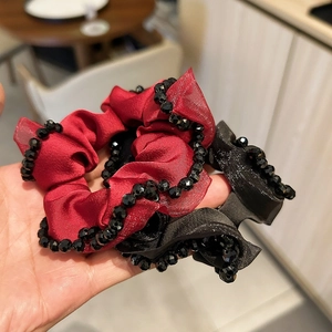 Close-up of handmade satin hair scrunchies with crystal beads in red and black colors
