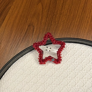 Pince à cheveux étoile en cristal rouge fait main sur fond de texture neutre