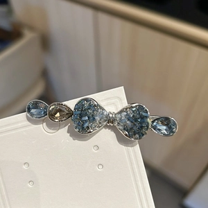 Detail view of rhinestone bow hair clip with blue crystals and silver alloy base