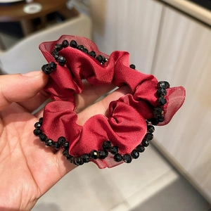 Detail of burgundy satin scrunchie with hand-sewn black crystal beads trim