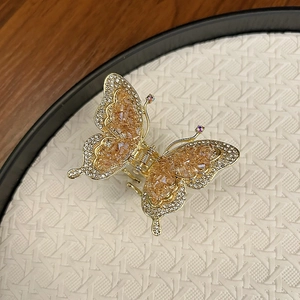 Pince à cheveux papillon dorée avec perles de cristal champagne et ailes ajourées