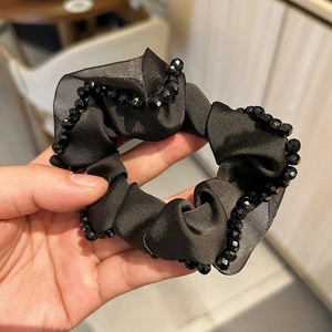 Detail of premium black satin scrunchie featuring hand-sewn crystal beaded edges