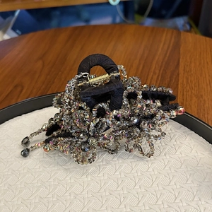 Detail of luxury hair claw featuring crystal beads, fringe tassels, and black fabric wrap