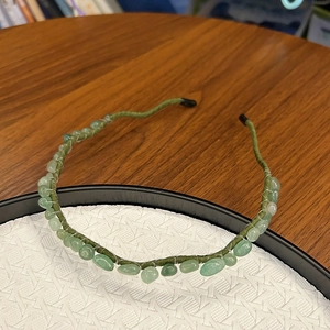 Detail of green beaded headband with handmade stone beads and woven thread on metal frame