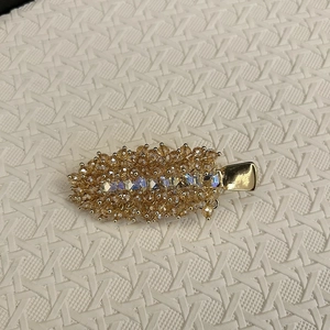 Detail of leaf-shaped hair clip with amber beads and iridescent square crystals