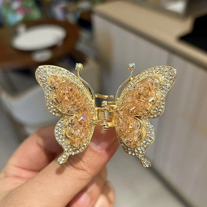 Détail de la pince à cheveux papillon avec cristaux champagne et base en métal doré