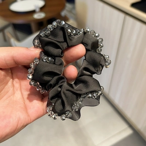Close-up of black satin scrunchie featuring hand-stitched crystal beads on the edges