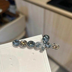 Detail of luxury crystal butterfly hair clip with blue and amber stones on silver base