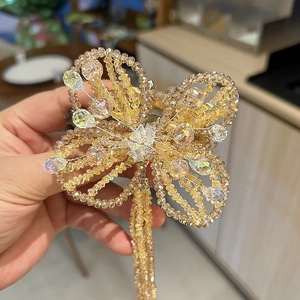 Close-up of handmade champagne crystal butterfly hair clip with elegant beaded tassels
