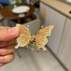 Détail de la pince à cheveux papillon dorée ornée de cristaux orange et de strass