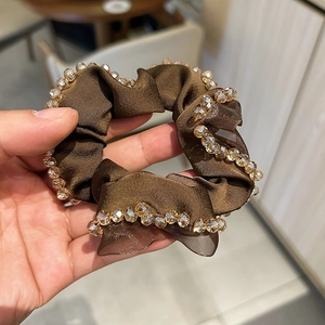 Detail of coffee brown satin scrunchie featuring crystal beads and silky texture
