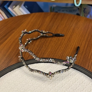 Detailed macro view of double-layer crystal headband with wavy black frame and clear beads