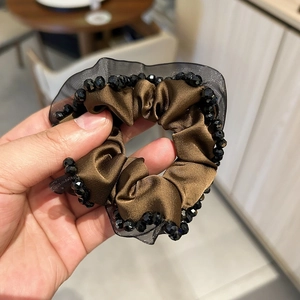 Detailed view of brown satin scrunchie with crystal beaded mesh edge and pleated texture