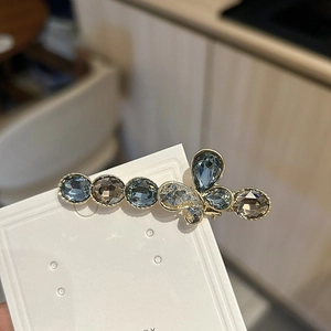 Detailed view of luxury crystal bow hair clip with blue and smoke grey stones