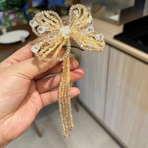 Handmade crystal butterfly hair clip with beaded tassels shown in hand closeup