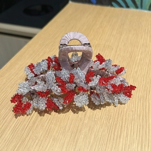 Détail d'une grande pince à cheveux avec perles en cristal rouges et blanches sur tissu