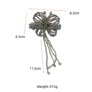 Detail view of handmade beaded butterfly hair clip with grey and green tassels