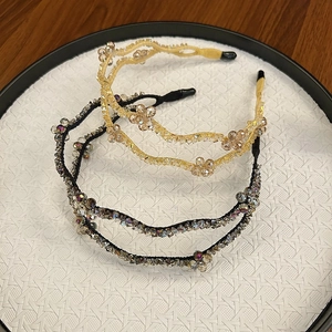 Detail of three handmade crystal beaded wave headbands in champagne and black on a tray