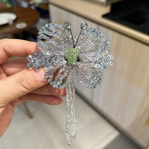 Detailed close-up of handmade blue crystal butterfly hair clip with beaded tassels