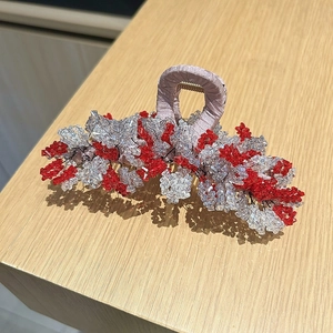 Détail de cristaux rouges et clairs sur une pince à cheveux en tissu rose pour femme