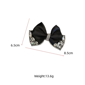 Detailed view of a black satin bow hair clip with rhinestones, 8.5cm by 6.5cm size