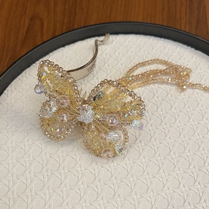 Close-up of handmade beaded butterfly hair clip with champagne crystals and gold metal clip