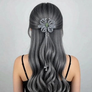 Detail view of flower hair clip with green gemstone and long sparkling fringe tassels