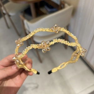 Elegant gold wavy crystal headband featuring floral accents and double-layer stones
