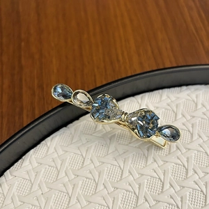 Detail of luxury bow hair clip with blue-gray crystals on a golden alloy base