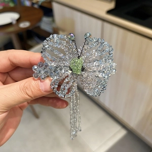 Close-up of handmade beaded butterfly hair clip with crystal tassels and light blue wings