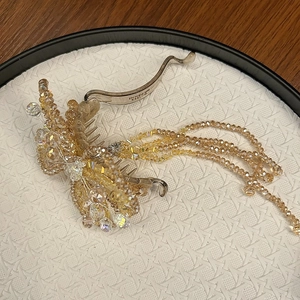 Elegant crystal butterfly hair clip with beaded tassels and silver finish on textured tray