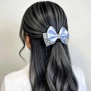 Elegant light blue satin bow hair clip with rhinestones worn on wavy brunette hair