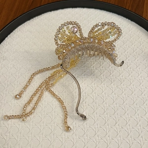Detailed macro view of beaded butterfly hair clip with champagne tassels and metal claw