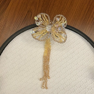 Detailed view of handmade crystal butterfly hair clip with beaded tassels and champagne stones
