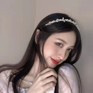 Détail d'un serre-tête doré avec perles blanches et cristaux sur un mannequin femme