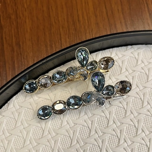 Detailed macro view of luxury crystal bow hair clips on a white textured tray
