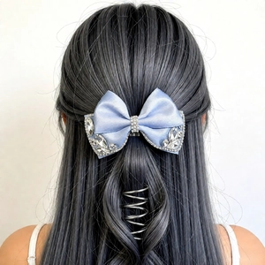 Detail of blue satin bow hair clip with sparkling rhinestones worn on braided hair